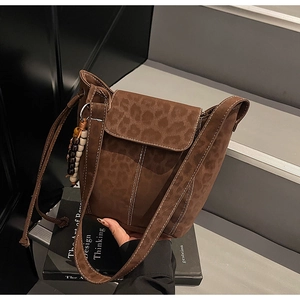 Macro view of leopard print bucket bag with contrast stitching and decorative beaded charm