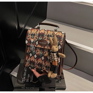 Close-up of geometric quilted texture fabric and premium brown leather trim of the handbag