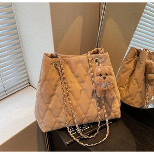 Detail of khaki quilted tote bag with gold logo, chain strap and cute bear charm pendant