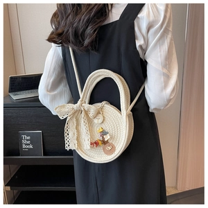 Detailed texture of straw woven round bag featuring lace bow and floral appliques