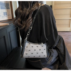 Detail of grey bow-print shoulder bag with black leather trim and silver metal buckle