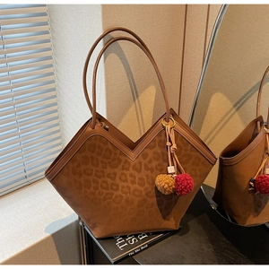 Detailed view of leopard print tote bag with V-shaped opening and decorative fur charms