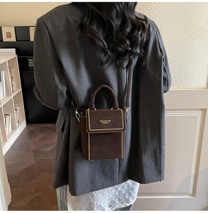Detail of brown suede crossbody bag with gold rivets and Nan Xiao Jie logo