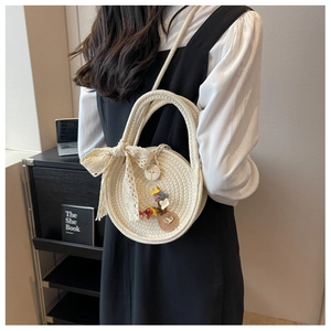 Detail of round straw bag featuring 3D flowers, lace bow, and elegant dual-strap design