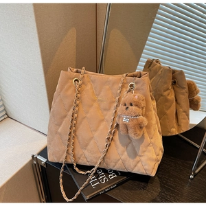 Detail of khaki quilted tote bag with metal chain strap and cute plush bear charm