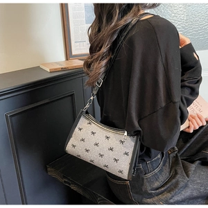 Side view of a French style shoulder bag with black bow patterns on grey fabric finish