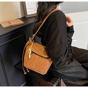 Detail of vintage brown bucket bag featuring leopard print flap and colorful beaded charm