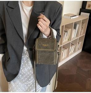 Detailed side view of structured dark green crossbody bag with gold rivet and top handle