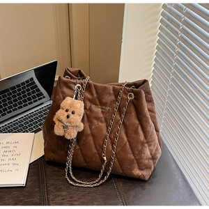 Detail of dark brown quilted tote bag with chain strap and cute puppy pendant accessory