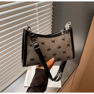 Detail showing grey wool texture underarm bag with black bow patterns and leather strap