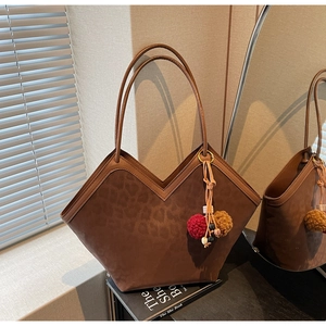 Detail of large leopard print tote bag with brown leather patchwork and furry pompom charm