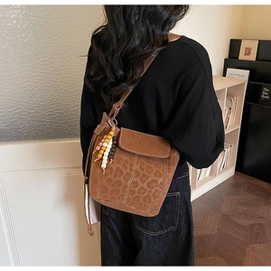 Detail of leopard print bucket bag featuring bohemian tassels and white topstitching
