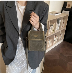 Detail view of small olive green box bag with gold rivets on a dark blazer suit