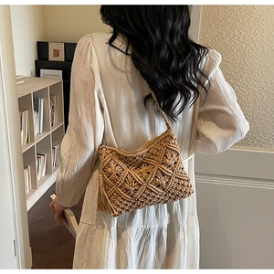 Detail of bohemian hand-woven straw bag with fringe tassel and intricate geometric patterns