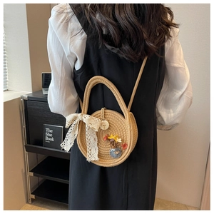Detail of round woven straw crossbody bag with white lace bow and floral patches
