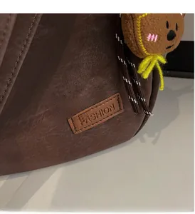 Détail du sac marron foncé avec étiquette en cuir et porte-clés ours en peluche doux
