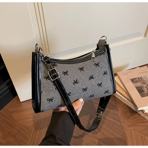 Detail of grey fabric shoulder bag with black bow patterns and leather edge trim