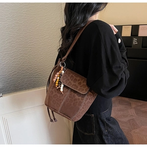Detail of leopard print suede bucket bag featuring ethnic style beaded tassel and flap