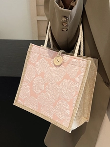 Pink rose jacquard tote bag with rope handles held by a model in a brown blazer