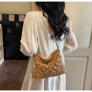 Detail of handmade macrame straw shoulder bag with fringe tassel on a model in white dress