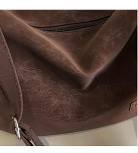 Gros plan sur la texture du cuir marron vintage et la boucle en métal d'un sac luxe