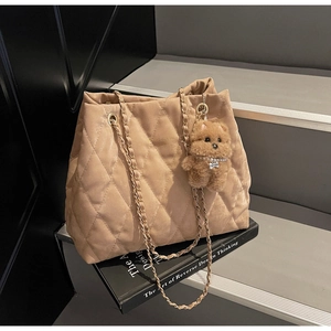 Detail of camel quilted tote bag with golden chain strap and plush puppy charm