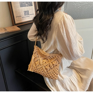 Detail of hand-woven straw shoulder bag featuring a zipper closure and tassel charm
