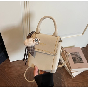 Close-up of off-white crossbody bag featuring gold stud rivets and plush ice cream charm