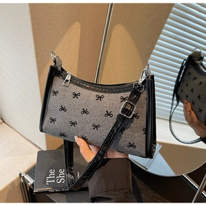 Detailed shot of retro shoulder bag featuring black bow patterns and leather strap