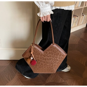Detail view of large leopard print tote bag with plush charm and suede-like finish