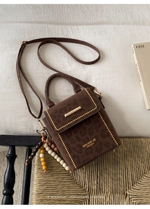 Detail of leopard print suede shoulder bag with gold hardware and colorful beaded charm