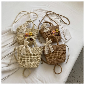 Detail view of handmade woven straw bags with floral embroidery and lace bow accents