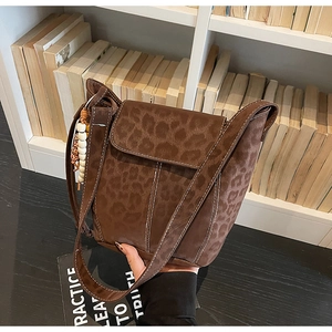 Close-up of leopard print crossbody bucket bag with decorative wood bead tassel detail