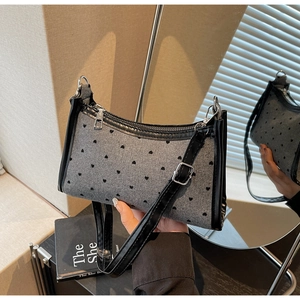 Detail of grey wool shoulder bag with black heart patterns and leather piping