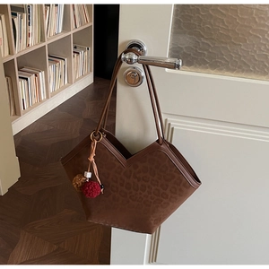 Detail of leopard print suede tote bag featuring a decorative plush pom-pom charm