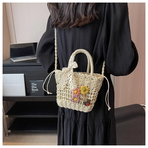 Detail of hand-woven straw crossbody bag with floral accents and lace bow detail