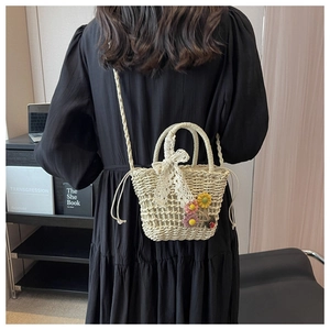 Detail of cream straw woven bucket bag featuring lace bow and handmade 3D floral accents