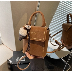 Detail of a brown leather bag featuring metal rivets and an ice cream charm accessory