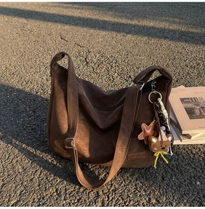 Détail du sac fourre-tout en daim marron avec logo de mode et charm ours en peluche