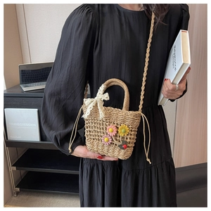 Close-up of hand-woven straw bucket bag with floral accents and a drawstring lining
