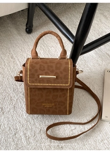 Detail of leopard print crossbody bag with gold buckle and rivet accents
