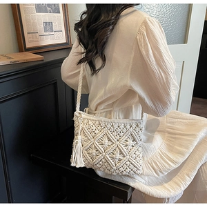 Detailed close-up of handmade cream woven shoulder bag with bohemian tassels and patterns
