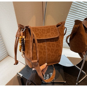 Detail of leopard print bucket bag with colorful wood bead charm and flap design
