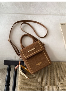 Close-up of leopard print suede crossbody bag with gold lock and wooden bead charm