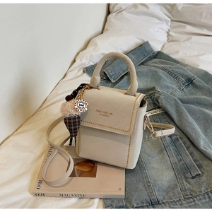 Detail of cream crossbody bag featuring yellow contrast stitching and ice cream charm
