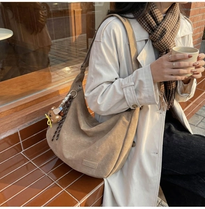 Détail du sac demi-lune en daim taupe avec bandoulière réglable et breloque ourson