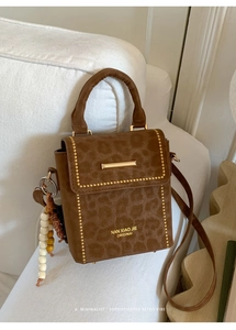 Detail of leopard print suede mini bag featuring gold studs and beaded strap charm