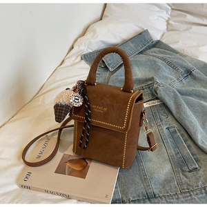 Detail of dark brown nubuck bag with gold bead trim and plush ice cream charm accessory
