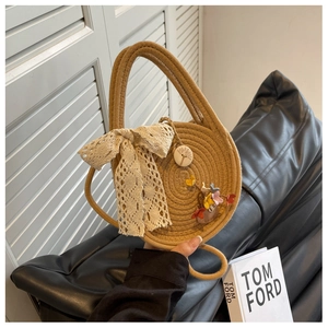 Detailed weave pattern of straw handbag with beige lace bow and floral bird charm
