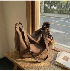 Détail du grand sac hobo marron vintage en similicuir mat avec un charm d'ours en peluche